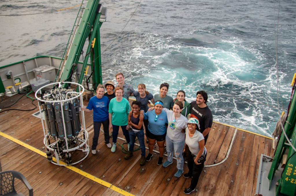 12 people stand together on the back deck of the R/V Walton Smith research vessel to take a cruise team photo.